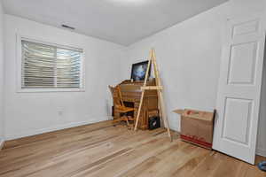 Office with visible vents, light wood-style flooring, a textured ceiling, and baseboards