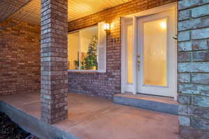 Property entrance featuring brick siding and covered porch