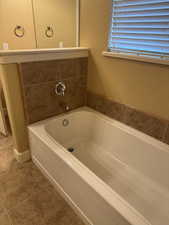 Full bathroom with tile patterned floors and a garden tub