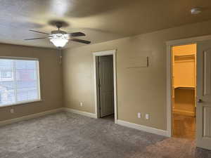 Unfurnished bedroom featuring baseboards, visible vents, carpet, and a walk in closet