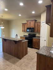 Kitchen featuring recessed lighting, a center island, decorative light fixtures, a breakfast bar, and black appliances