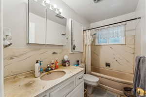 Bathroom featuring visible vents, shower / bath combo with shower curtain, toilet, and vanity