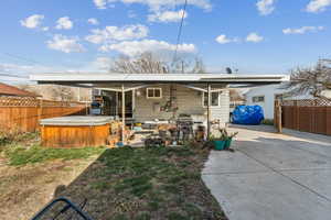 Back of property with a patio, a fenced backyard, and a hot tub