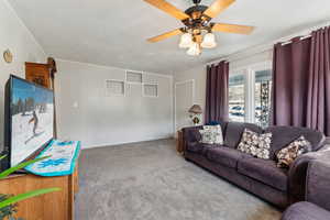 Carpeted living room featuring a ceiling fan