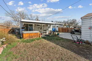 Back of property featuring a patio, a fenced backyard, and a hot tub