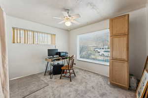 Home office with light carpet, baseboards, and a ceiling fan