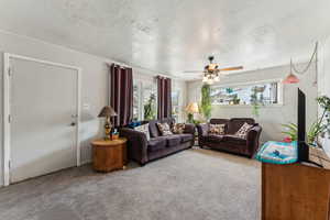 Carpeted living room featuring a textured ceiling and a ceiling fan