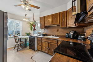 Kitchen with range with electric cooktop, a ceiling fan, a sink, freestanding refrigerator, and brown cabinetry