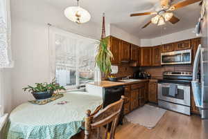 Kitchen with backsplash, ceiling fan, light wood-style flooring, stainless steel appliances, and a sink