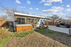 Rear view of property with a hot tub, a fenced backyard, and a patio area