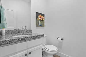 Bathroom with vanity, toilet, wood finished floors, and baseboards