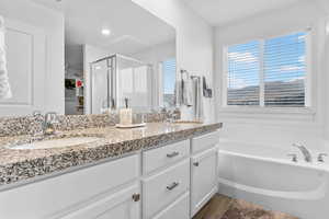 Bathroom with double vanity, a shower stall, a garden tub, and a sink