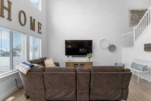 Living area with light wood-style flooring, baseboards, a high ceiling, and a healthy amount of sunlight