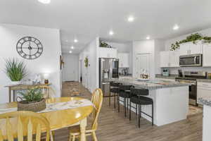 Kitchen featuring a center island, white cabinetry, stainless steel appliances, and light wood-type flooring