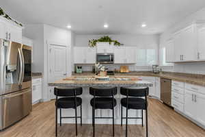 Kitchen with a breakfast bar, white cabinetry, and stainless steel appliances