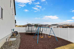 View of jungle gym featuring a trampoline and a fenced backyard