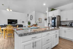 Kitchen with a kitchen island, recessed lighting, white cabinets, stainless steel fridge with ice dispenser, and light wood finished floors