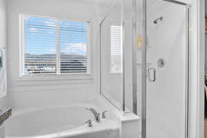 Bathroom featuring a garden tub and a shower stall