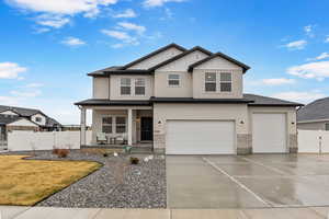 View of front of home featuring driveway, stone siding, a porch, fence, and an attached garage