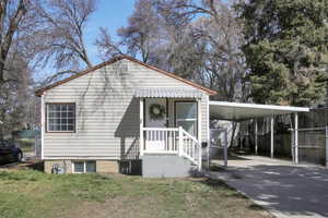 View of front of property featuring a front lawn, an attached carport, driveway, and fence