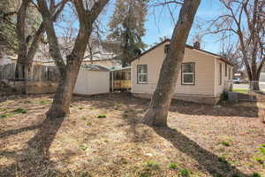 Back of property with a shed, central AC, a chimney, a fenced backyard, and an outdoor structure