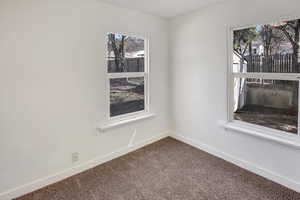 Unfurnished room with dark colored carpet and baseboards