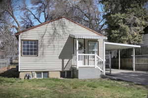 Exterior space featuring a carport, a lawn, driveway, and fence