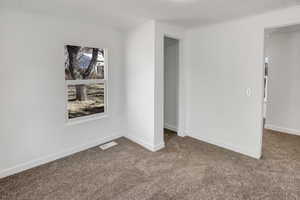 Carpeted empty room with visible vents and baseboards