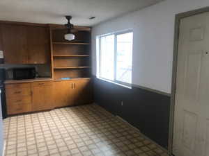 Interior space with light floors, visible vents, open shelves, light countertops, and black microwave
