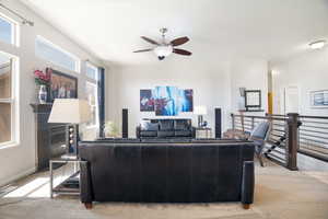 Living area with visible vents, a ceiling fan, light carpet, and baseboards