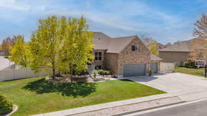 View of property hidden behind natural elements featuring brick siding, fence, and a front lawn