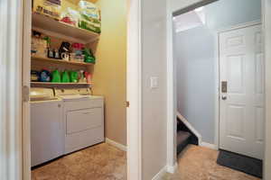 Clothes washing area with washer and dryer, laundry area, and shelving