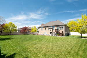 Back of house with a yard, stucco siding, and a fully fenced backyard
