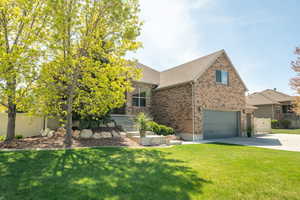 View of front facade with concrete driveway, fence, brick siding, a front lawn, and a garage