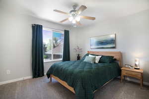 Carpeted bedroom featuring ceiling fan, window coverings and baseboards