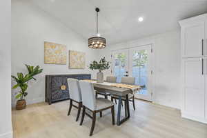 Dining room featuring vaulted ceiling, a chandelier, and LVP flooring and french doors leading out to backyard patio space.