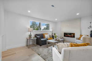 Basement living room with recessed lighting, LVP flooring and a large window and Gas fireplace.