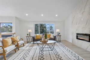 Main living area featuring recessed lighting, lvp flooring, expansive windows and gas fireplace.