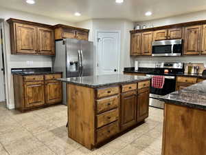 Kitchen featuring light tile patterned floors, stainless steel appliances, a center island, and recessed lighting