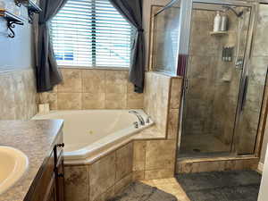 Bathroom with tile patterned floors, vanity, a jetted tub, and a shower stall