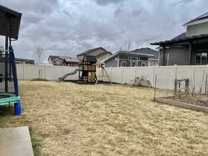 View of yard with a playground, a trampoline, a fenced backyard, and a vegetable garden