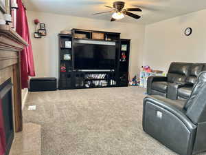 Carpeted living room with a ceiling fan and a tiled fireplace