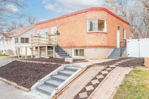 Rear view of property featuring a gate, stairway, brick siding, and fence