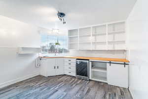 Kitchen featuring open shelves, wine cooler, wood finished floors, and wooden counters