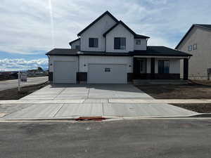 Modern inspired farmhouse with a porch, concrete driveway, a garage, and board and batten siding