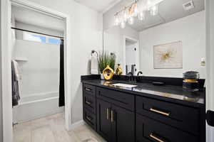 Bathroom featuring tile patterned floors, visible vents, shower / bath combo with shower curtain, a textured ceiling, and vanity