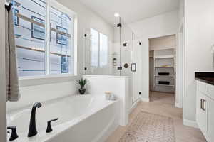 Bathroom featuring a shower stall, tile patterned flooring, a spacious closet, a bath, and vanity