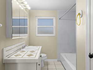 Bathroom with toilet, tile patterned flooring, tub / shower combination, baseboards, and vanity