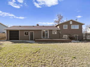 Back of house with fence, stucco siding, cooling unit, a yard, and a garage