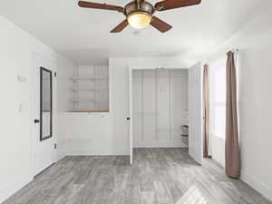 Unfurnished bedroom featuring a closet, light wood finished floors, baseboards, and ceiling fan